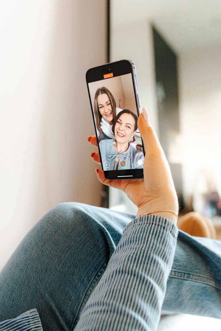 Henkilö farkuissa ja raidallisessa paidassa ottaa selfien älypuhelimella; näytöllä näkyy hymyilevä kaksikko poseeraamassa yhdessä sisätiloissa. Kuva on ST Creative Studion kotisivuilla.